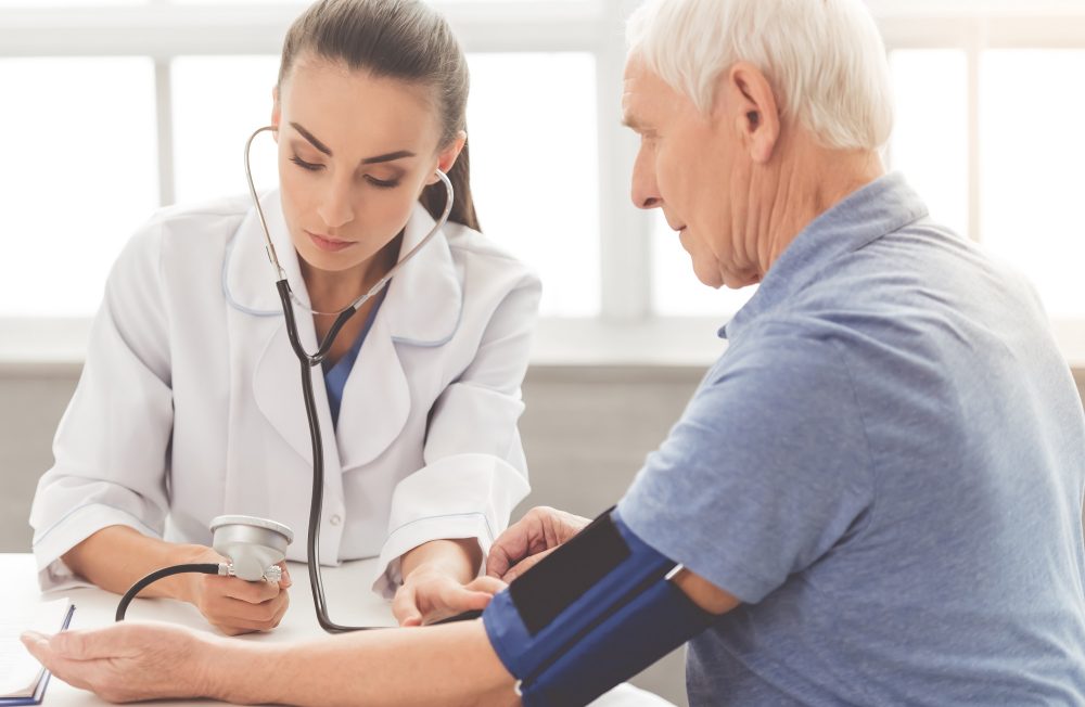 Doctor in medical coat is testing patient blood pressure.